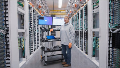 Close up image of female datacenter employee in cold aisle smiling.