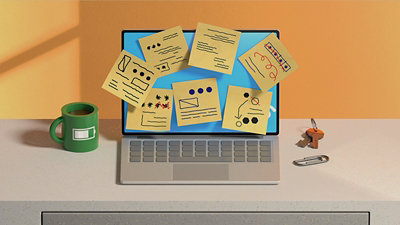 Computer sitting in a desk with sticky notes stuck to the screen