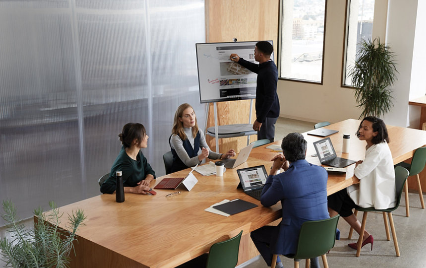 モダンな会議室で Surface Laptop を使い共同作業を行っている同僚たち。 