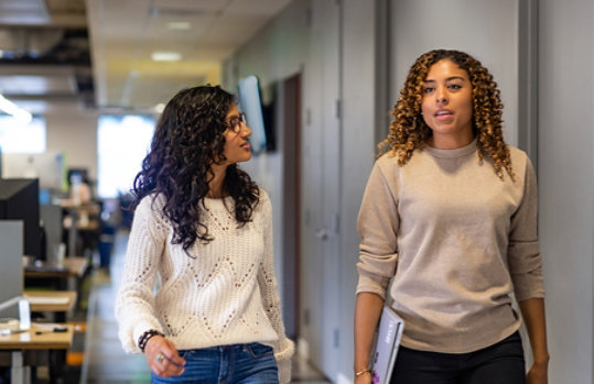 Two women talking and walking in a law office.