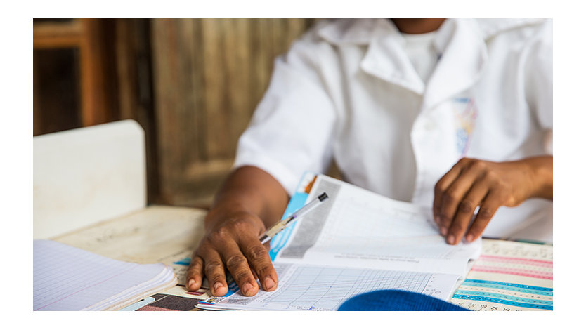 Uma médica examina documentos, incluindo gráficos de medição de estatura, como parte de um programa de aprimoramento da alimentação em Madagascar.