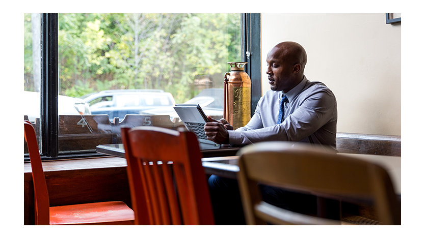 Remote business professional sitting in café using a convertible laptop as a tablet.