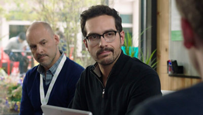 Dois personagens do vídeo de treinamento da SBC estão em um café conversando com uma terceira pessoa.