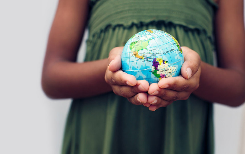 A small globe held in a young girl’s cupped hands. 