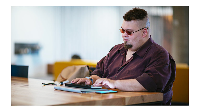 Um homem cego digita em um teclado braille enquanto trabalha em um celular.