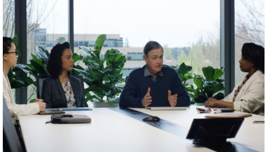 A group of office workers sit around a conference table having a discussion.