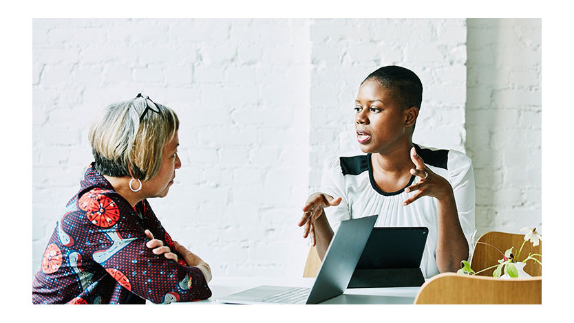Two women talking in office setting