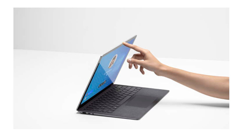 Side angle view of a female hand opening a Surface Laptop. 