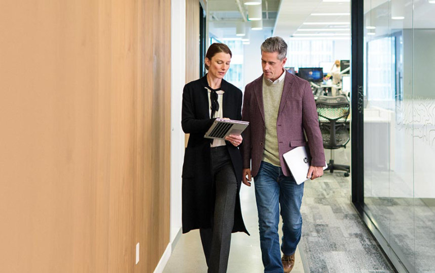 A man and woman walk in an office setting 
