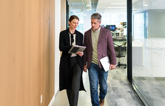 A man and woman walk in an office setting.