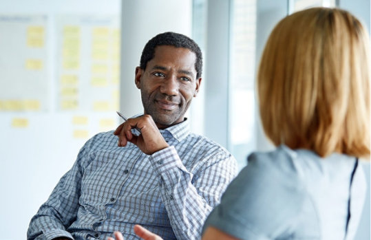 Two colleagues talking together while sitting in a modern office.