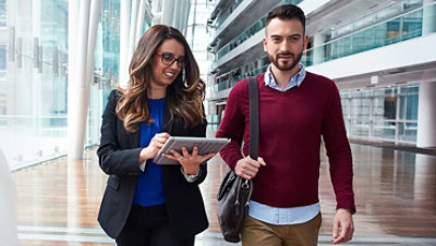 Um homem e uma mulher caminham lado a lado em um prédio comercial.