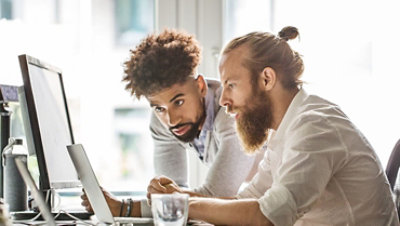 People in a office discussing work over a laptop.