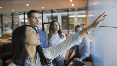 Businesspeople in a meeting room pointing at a projection screen.