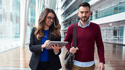 A man and woman walk side by side inside of an office building.
