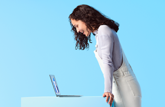 Woman standing and looking down at a Windows laptop