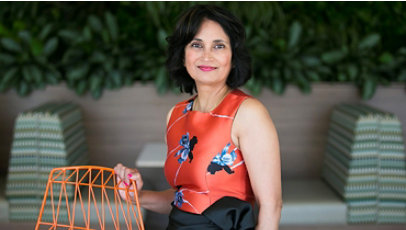 Microsoft Board Member Padmasree Warrior standing next to a chair, smiling.