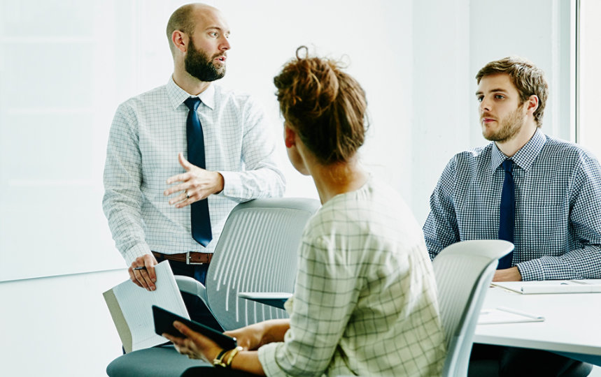 Businessman leading a project discussion with two colleagues in a conference room. 