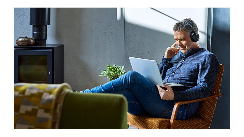 Man wearing headphones listening to music on a laptop.