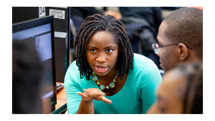 Teacher working with high school students in a computer lab.