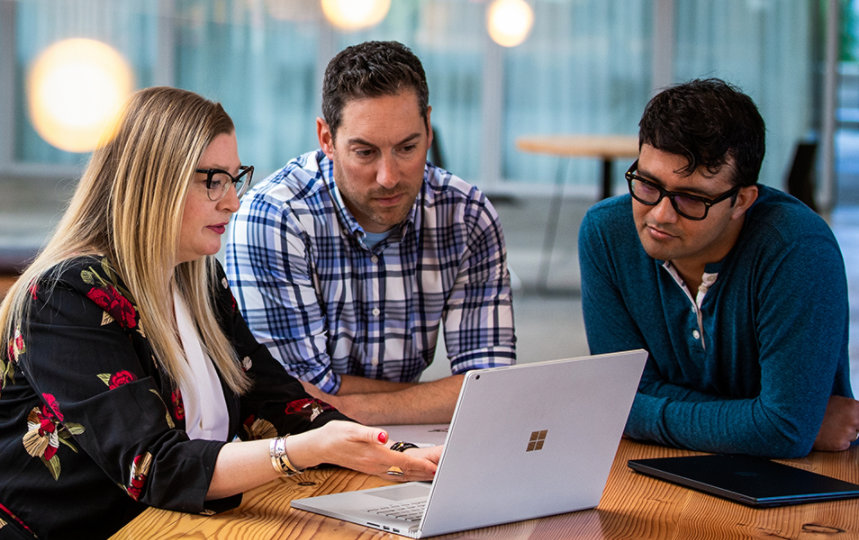 Three tech workers meeting in a common office space.