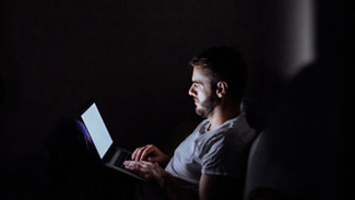 深夜，一位男士正在用笔记本电脑上网。