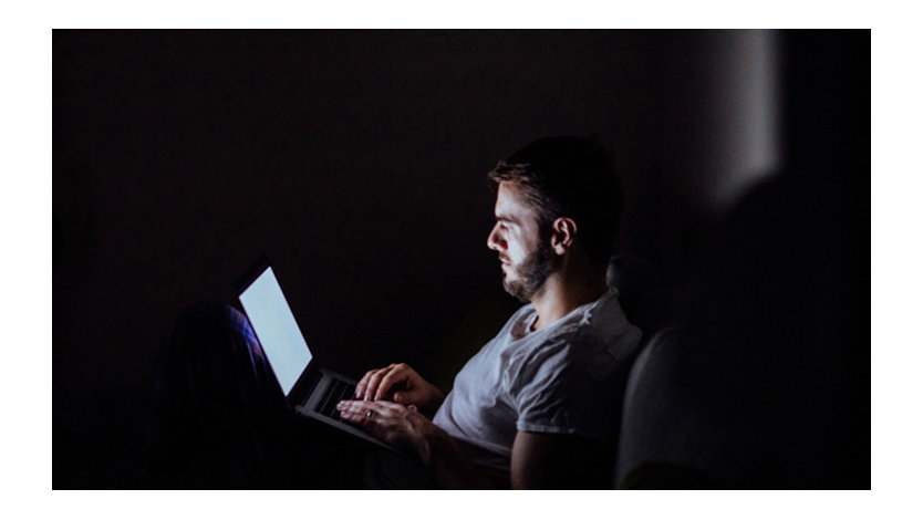 Man exploring the Internet on a laptop late at night.