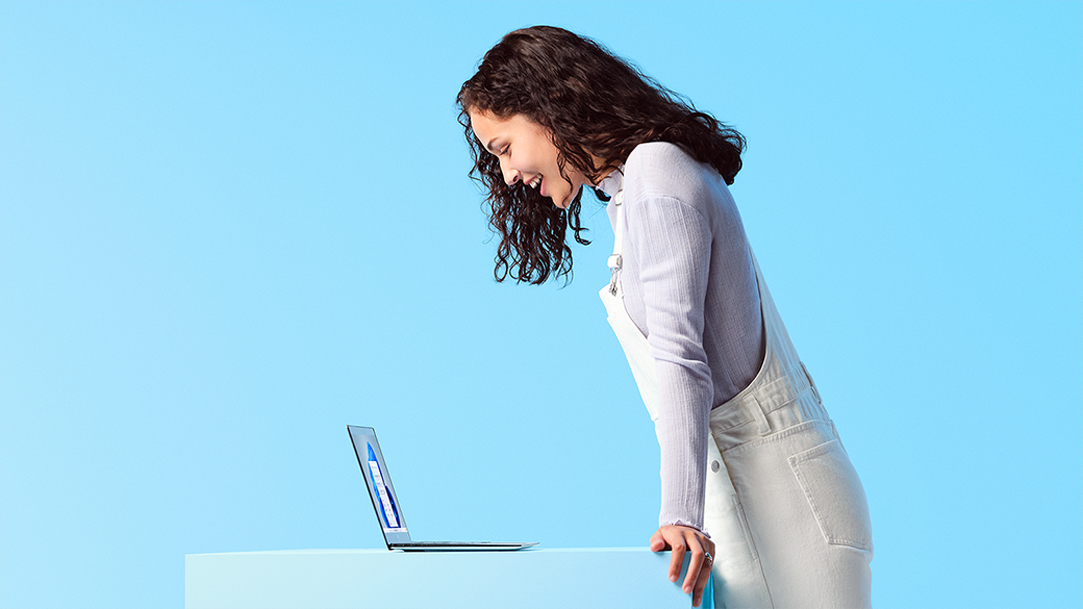 Woman standing and looking down at a Windows laptop