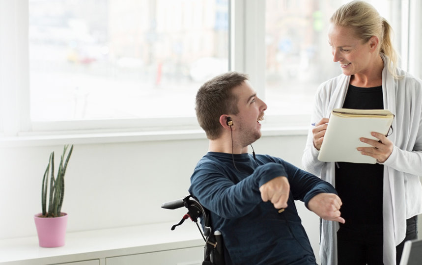 Disabled businessman discussing work with colleague in office. 