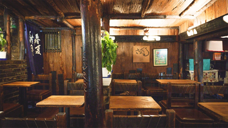 テーブルと椅子のある部屋、おそらくレストランまたはダイニング エリア。家具は木製のようで、部屋には壁と天井があります。