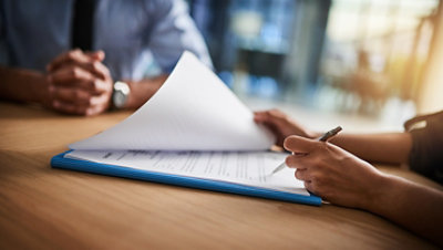 Cropped shot of a man and woman completing paperwork together at a desk.