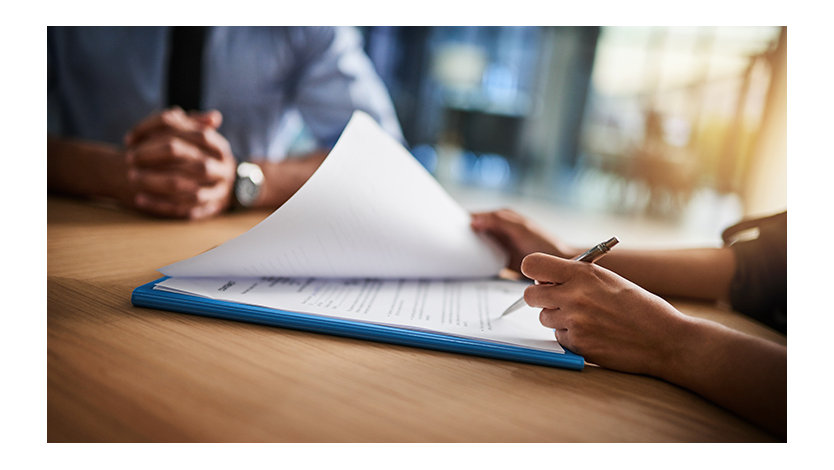 Cropped shot of a man and woman completing paperwork together at a desk.