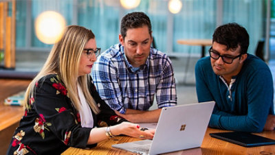 Three tech workers meeting in a common office space.