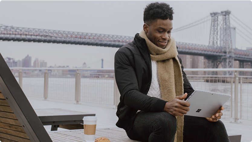 Man sitting outside with a laptop in his hands with illustrated Christmas decorations