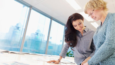 工作室裡兩名女子在平板電腦上審查計劃。