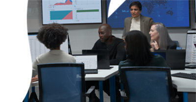 Grupo de trabajadores en sus puestos de trabajo con equipos de escritorio en funcionamiento.