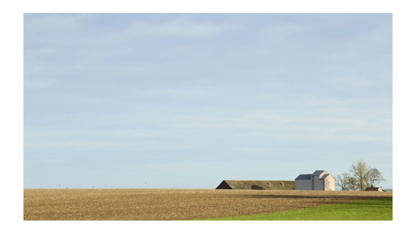 Barn in a field against a blue sky.