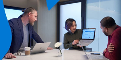 Một người đang chỉ cho hai đồng nghiệp dữ liệu trên máy tính xách tay.