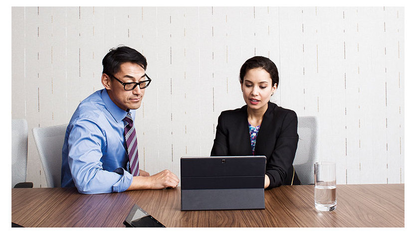 Two people at a table looking at a laptop