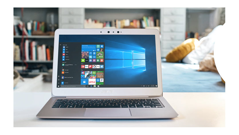 An open laptop sits on a low table in front of a bookshelf in a sitting room.