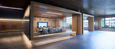 Un uomo con camice blu in piedi davanti al portatile, con pareti a strisce verticali blu e bianche sullo sfondo.