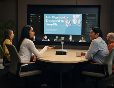 A man in a blue shirt interacts with a touchscreen display in a server room, focusing on monitoring data.
