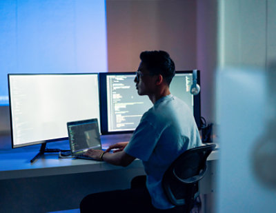 A man sitting at a desk using a laptop.