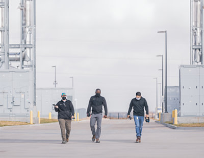 Gruppo di uomini che camminano su una strada sotto un cielo nuvoloso.