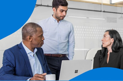 Tres compañeros de trabajo conversan en un escritorio.