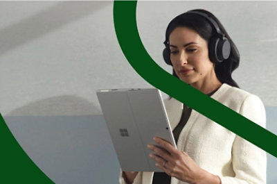 A person wearing over the ear headphones and using a tablet.