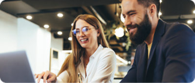 Két személy egymás mellett ül és egy laptop képernyőjét nézi.