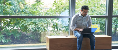 A man sitting on a bench using a laptop.