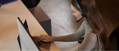 A person wearing a headset and using a computer