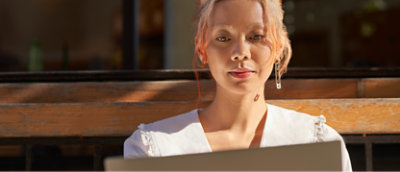 Femme assise sur un banc avec un ordinateur portable.